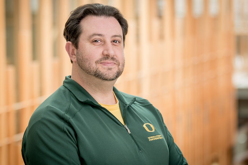 Joshua Puhn wearing a yellow shirt and a dark green "O" branded pullover