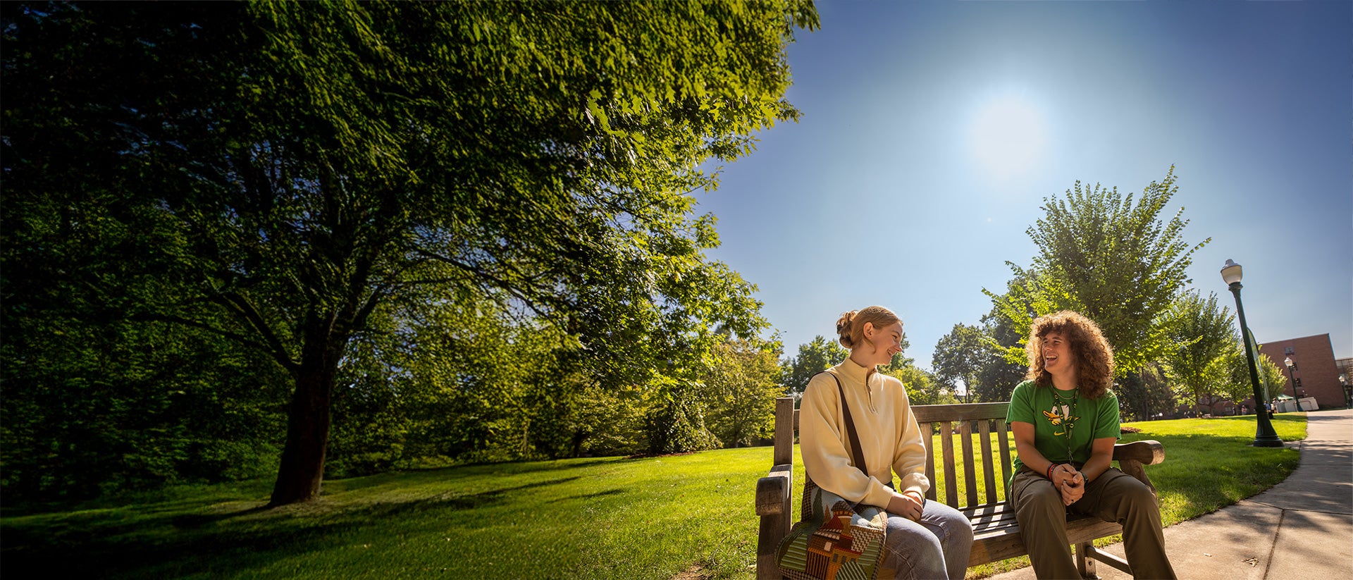 Two students talking and sitting on a bench