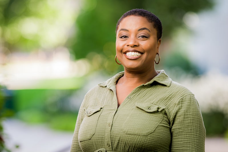 woman with short black hair wearing a sage green sweater
